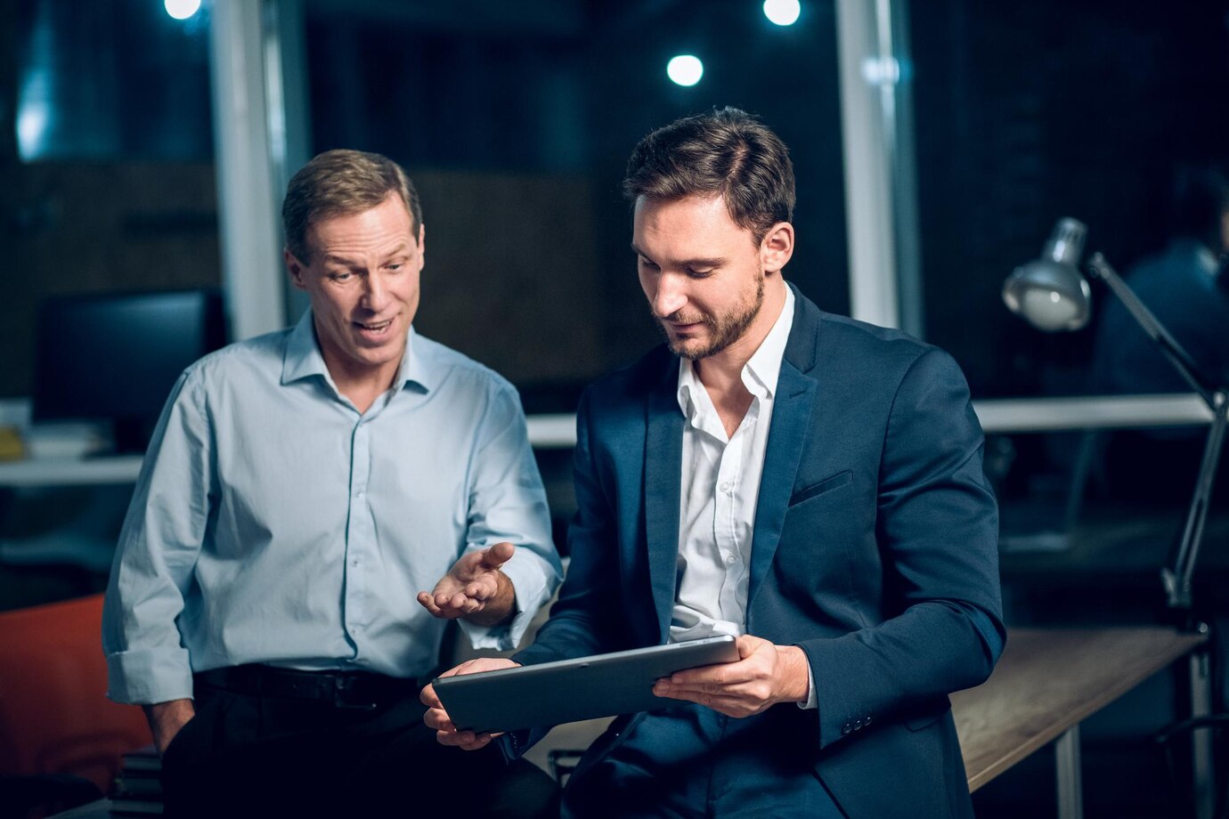 two-office-workers-with-tablet-office-late-night-young-businessmen-talking-while-viewing-presentation-digital-touchscreen-tablet_549566-692